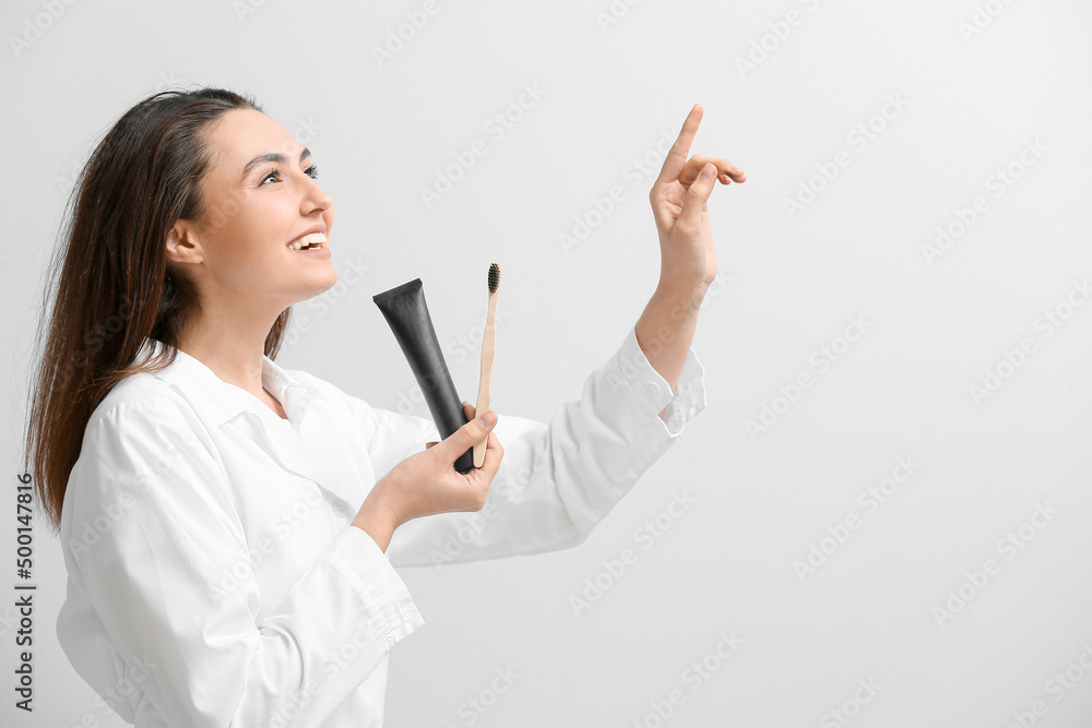 Beautiful young woman with activated charcoal tooth paste and brush on light background Beautiful young woman with activated charcoal tooth paste and brush on light background