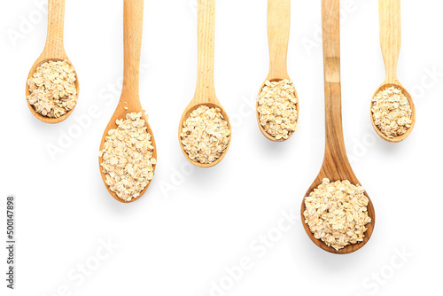 Spoons with raw oatmeal flakes on white background