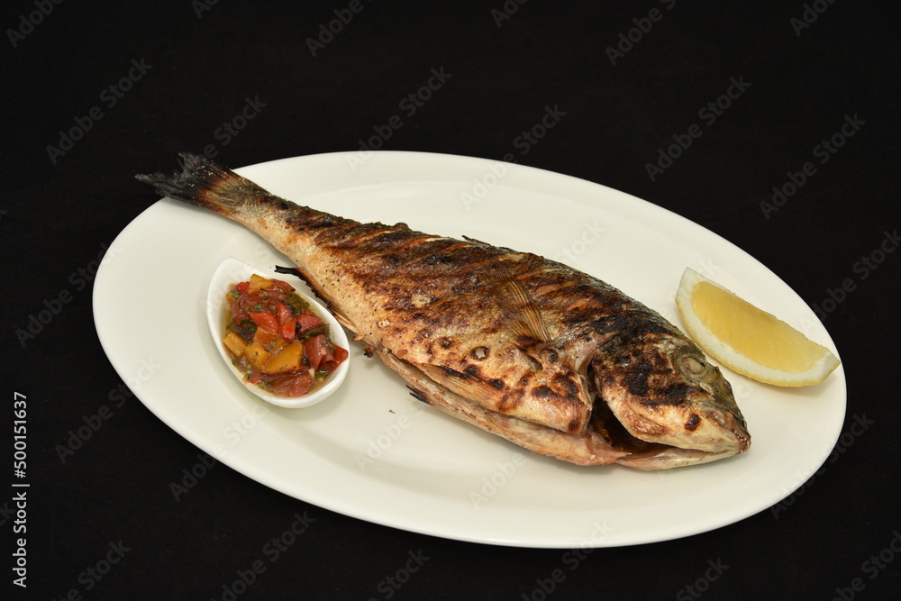 Roasted fish with lemon slices and spicy sauce,dorada Roasted fish with lemon slices and spicy sauce,dorada