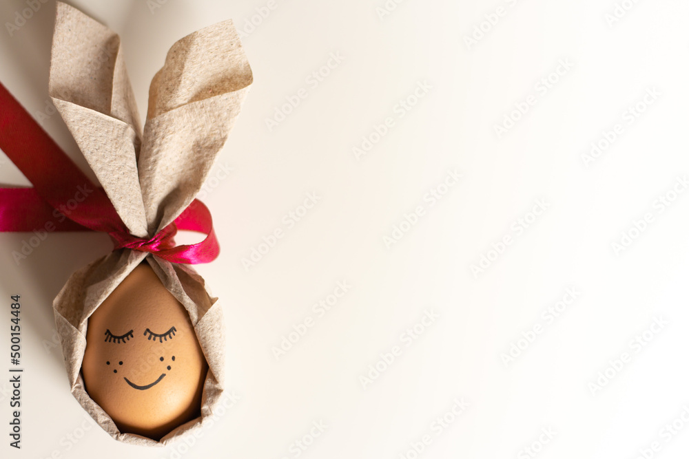 Creative easter egg with a cute face painted on a light background. Happy Easter concept. Top view, mockup, template, copy space Creative easter egg with a cute face painted on a light background. Happy Easter concept. Top view, mockup, template, copy space