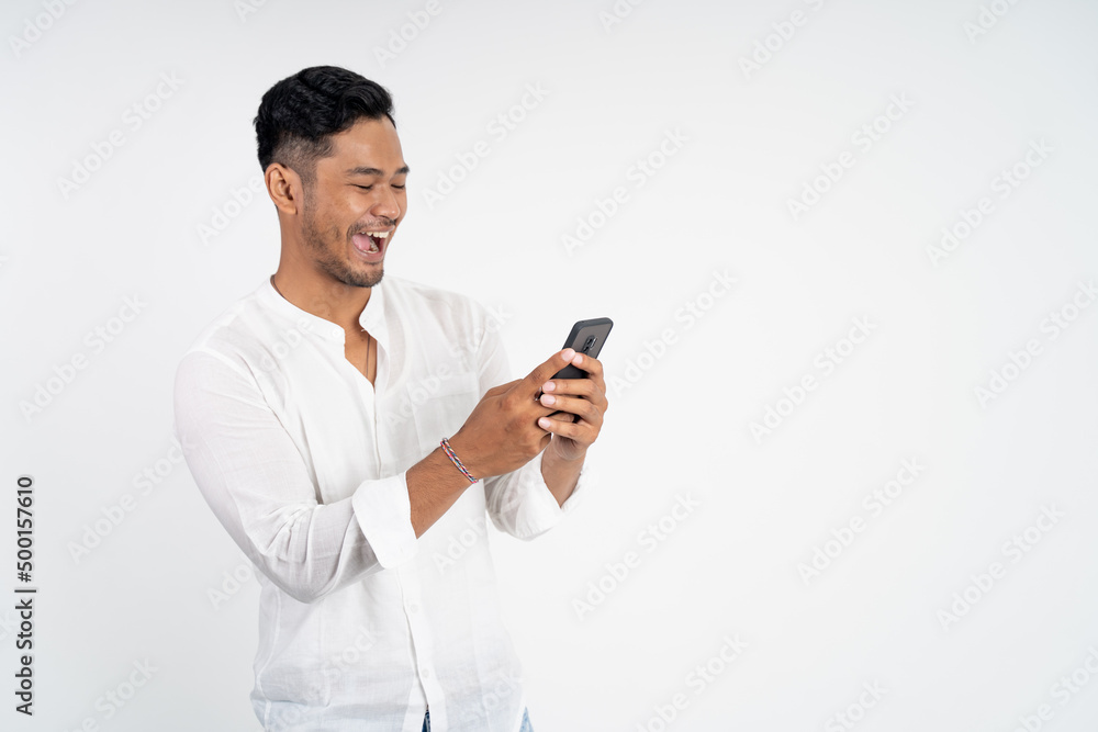 happy asian young man looking at the screen of a mobile phone on isolated background happy asian young man looking at the screen of a mobile phone on isolated background