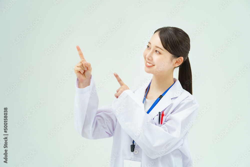 指を立てるポーズをする白衣の女性 