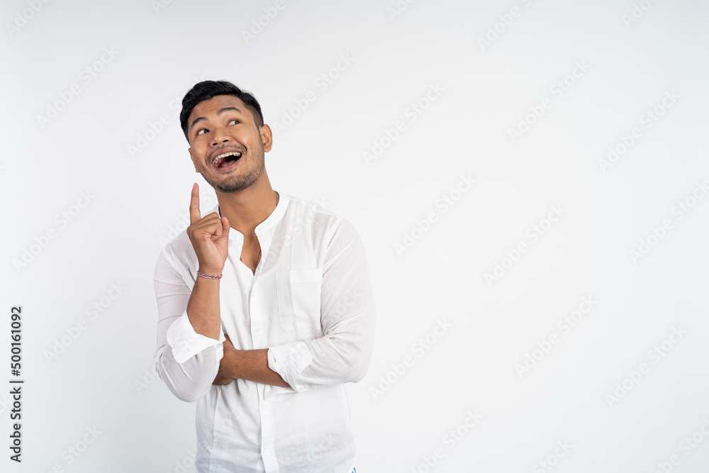 young asian man laughing with finger pointing for finding idea while standing on isolated background young asian man laughing with finger pointing for finding idea while standing on isolated background
