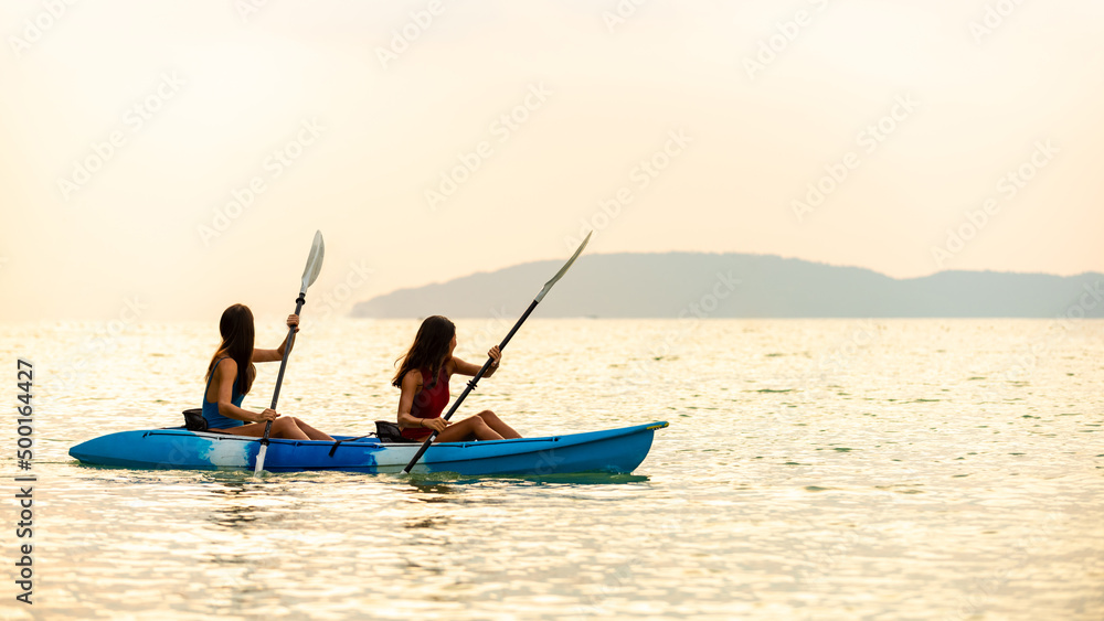 Naklejka premium Young beautiful Asian woman kayaking in the sea together at tropical island on summer vacation. Happy female friends enjoy and fun outdoor activity lifestyle and water sports on beach holiday vacation