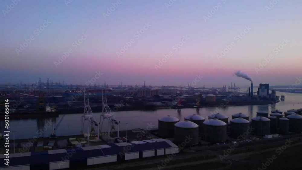 Aerial View of Maasvlakte Industrial Port Against Purple Skies, Pan Right To Orange Sunset In Distance Aerial View of Maasvlakte Industrial Port Against Purple Skies, Pan Right To Orange Sunset In Distance