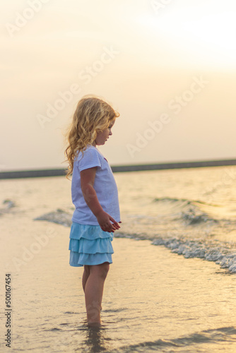 Shot of a little girl playing on the beach during sunset hour. Kids