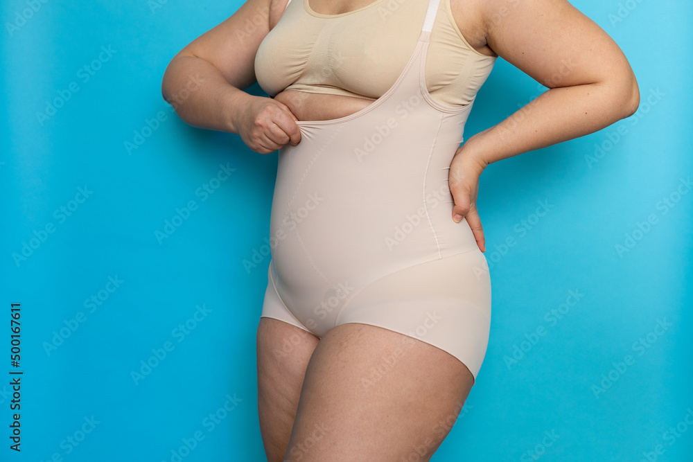 Premium Photo  Plus size woman in beige underclothes pulling shapewear  panties over belly closeup tighten figure and wear lifting underwear for  weight loss blue background concept of diet and fighting overweight