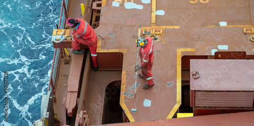 Fotografia, Obraz Seaman ship crew priming and derusting vessel deck for upcoming painting
