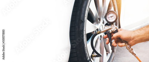 Foto A auto mechanic inflates a tire with an air tire inflating gun,horizontal copy s