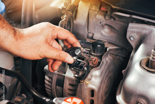 The auto mechanic hand is grasping the car alternator charger plug