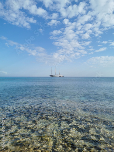 The largest sailing yacht in the world, an eight-deck motorsailer on the Mediterranean coast against a blue sky with beautiful clouds.