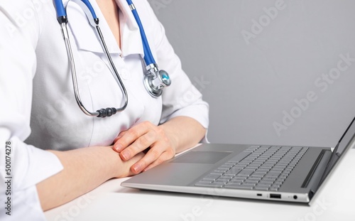 Doctor with stethoscope giving online consultation to patient. Healthcare and telemedicine concept. Woman in lab coat sitting at desk with laptop and making diagnosis remotely. High quality photo