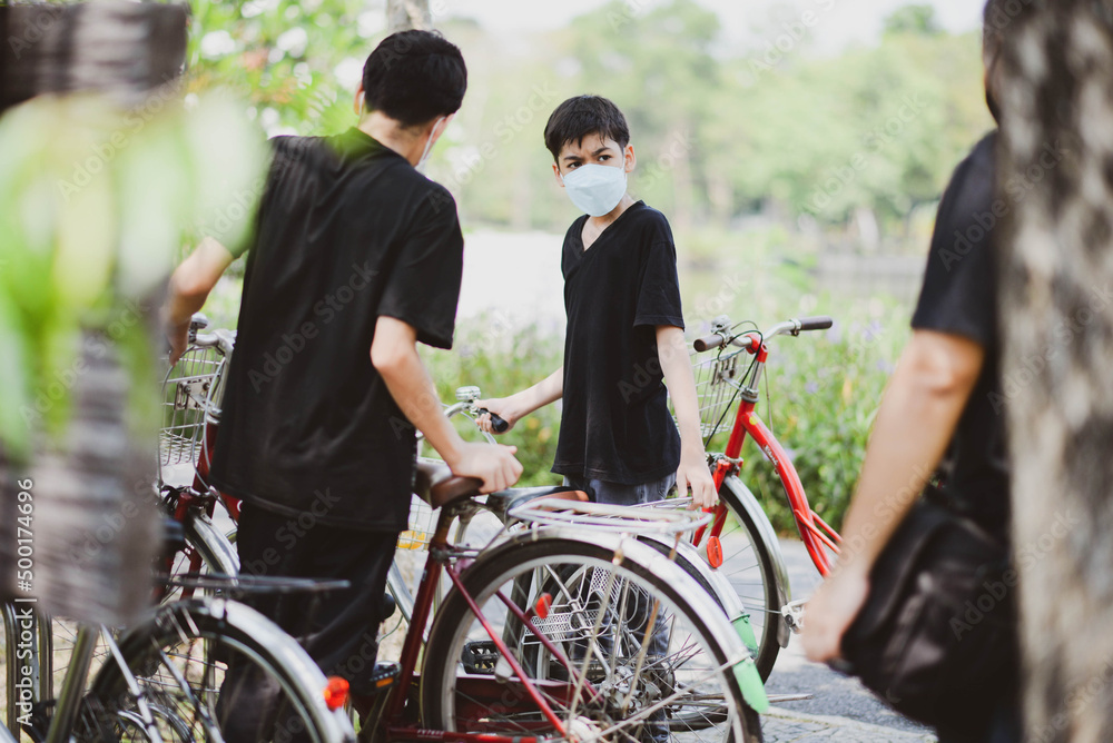 Obraz premium Teenager boy riding bicycle in the park with happy family
