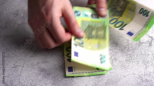 Male hands counting European 100 hundred Euro money banknotes and leave them on concrete background
