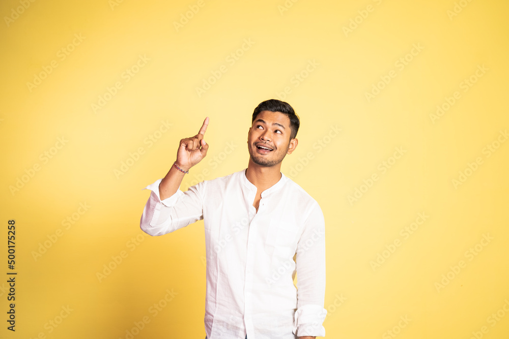 smiling asian young man with finger pointing up on isolated background smiling asian young man with finger pointing up on isolated background