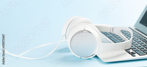 Headphones and laptop over blue background