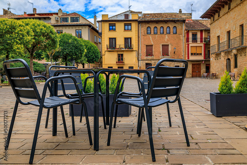Table and chairs at an outdoor cafe on a city plaza surrounded by medieval stone houses in Olite, Spain famous for a magnificent Royal Palace castle © SvetlanaSF