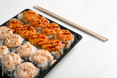 Delivery set of baked hot yaki maki rolls and chopsticks on white table, close-up. Japanese traditional sea food, Asian cuisine