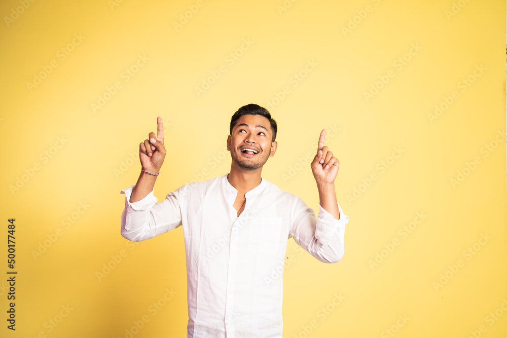 excited asian young man with two fingers pointing up on isolated background excited asian young man with two fingers pointing up on isolated background