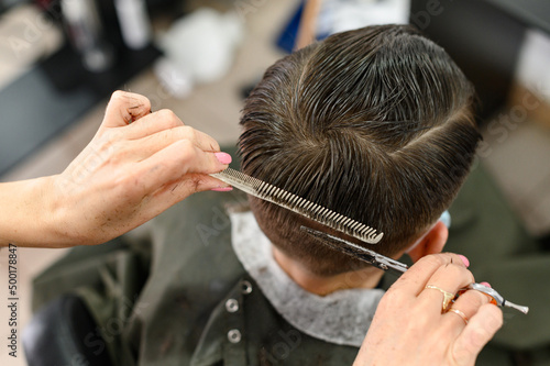 Teen guy gets a haircut during a pandemic at the barbershop, haircut and drying hair after a haircut. © Niko_Dali