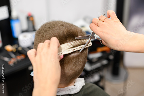 little boy in a mask, which is cut in the barbershop in the barbershop, fashionable and stylish haircut for a child.