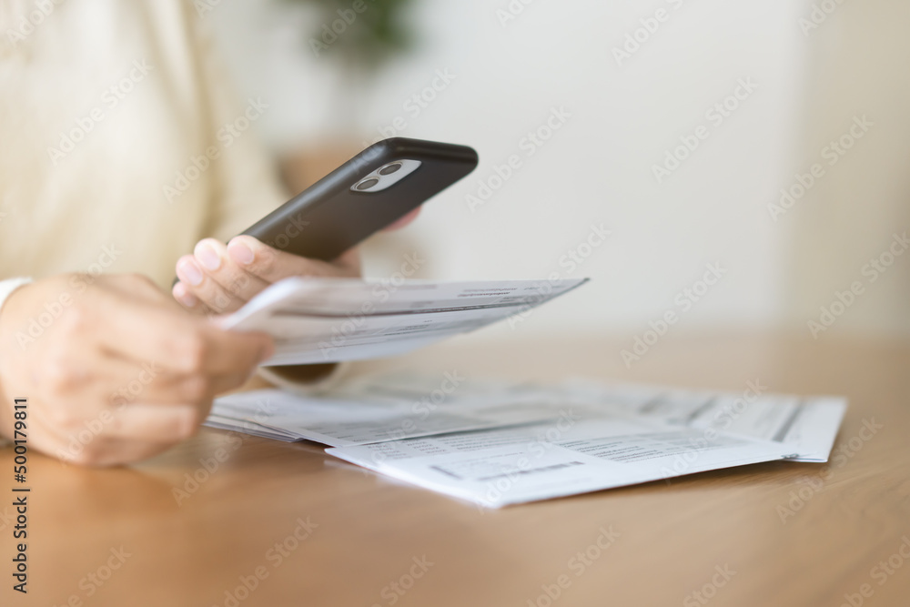 Fototapeta premium Woman paying bills using mobile phone. Cashless payment concept.