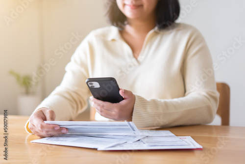 Woman paying bills using mobile phone. Cashless payment concept.