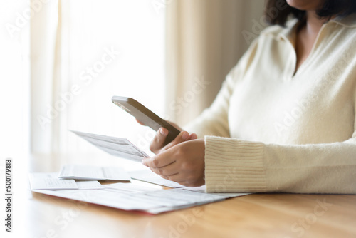 Woman paying bills using mobile phone. Cashless payment concept. photo