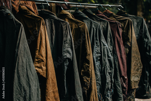 Collection of wax jackets on hangers in the shop. Many vintage men's jackets. Background and closeup texture of wax jackets.