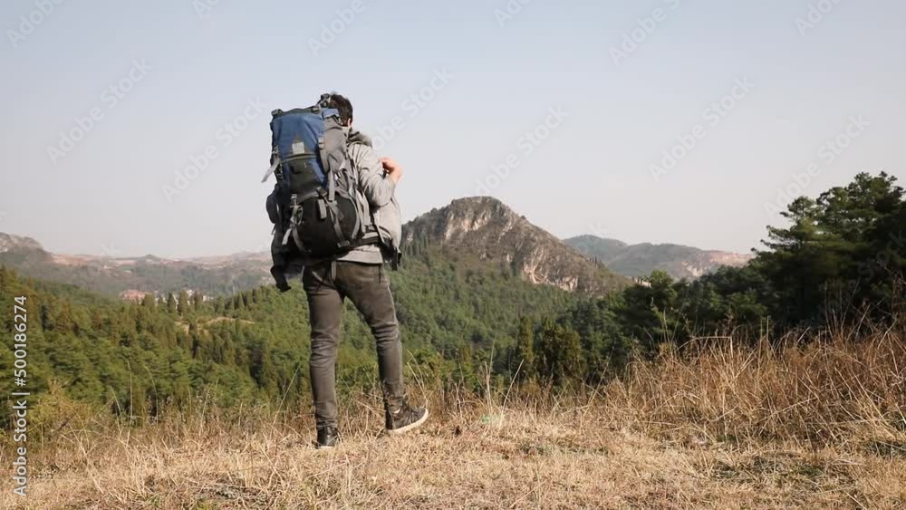Young man hikes in the mountains, takes down his backpack and watches the landscape Young man hikes in the mountains, takes down his backpack and watches the landscape