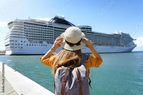 Tourist girl with backpack and hat standing in front of big cruise liner photo