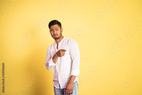 young asian man wearing white shirt with disdain expression pointing finger on isolated background