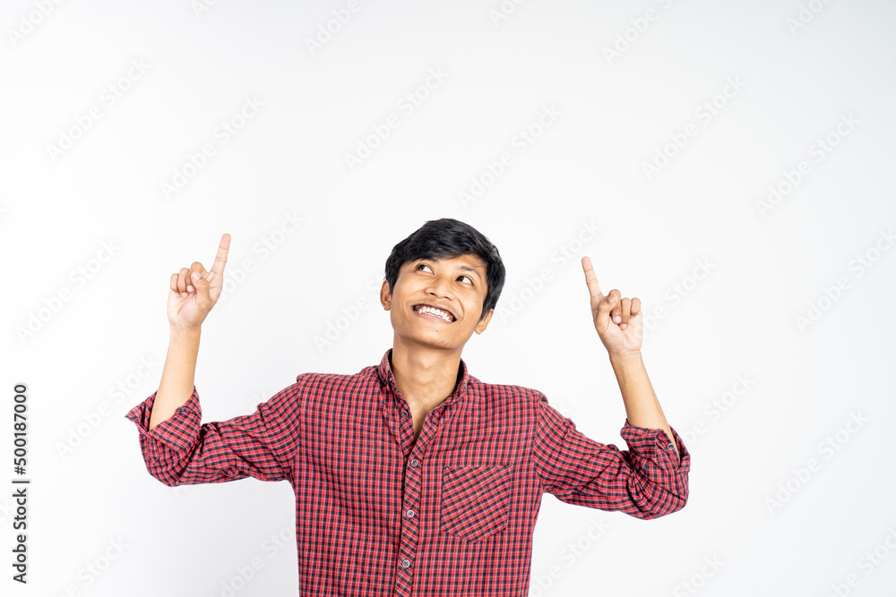 excited asian young man with two fingers pointing up on isolated background excited asian young man with two fingers pointing up on isolated background