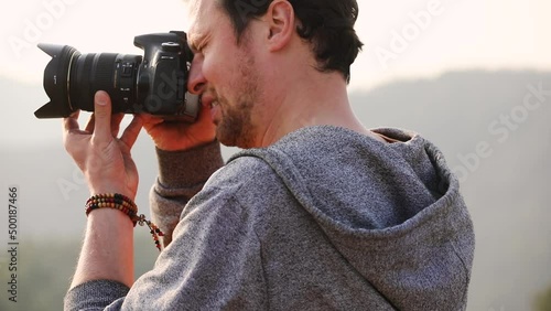 Close up on a photographer taking a photo in the nature during hiking on sunny day photo