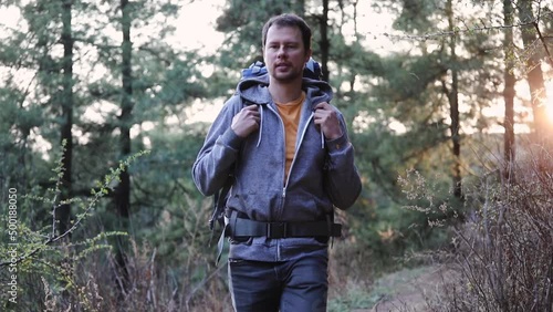 Young handsome man hikes in the forest with a backpack