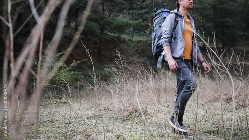 Young Caucasian man hikes in the nature with a big backpack