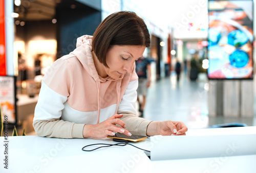 young businesswoman is working with her phone while charging the battery. Female holding smartphone while charging it in public place. she is entertained while she waits for her flight at the airpor photo