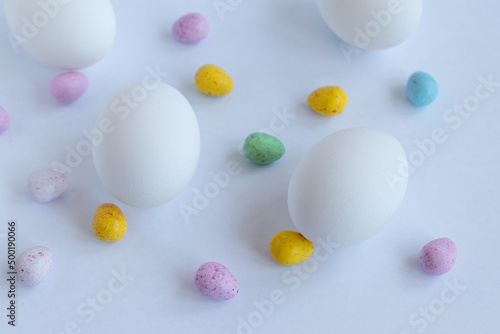 Easter background. White chicken eggs and colored chocolate eggs on a white background. Easter. Spring background. Food.