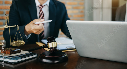 Male judge in a courtroom the gavel, working with digital tablet computer on wood table in sun light.