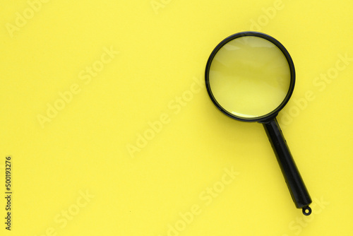 Black magnifier on a yellow background.