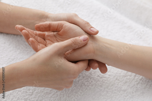 Woman receiving hand massage on soft towel, closeup photo
