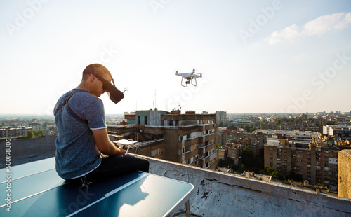 Tablou canvas Young technician man flying UAV drone with remote control in city