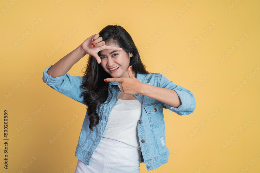 young woman looking at the camera from between fingers forming a frame on isolated background young woman looking at the camera from between fingers forming a frame on isolated background