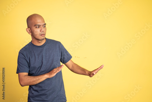 asian bald young man rejecting offer with both palms on isolated background