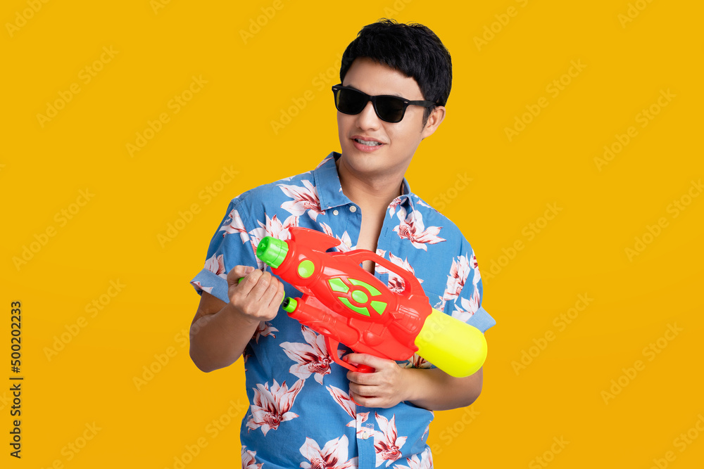 Young Asian man in summer outfits holding water guns plastic for Songkran festival in Thailand. Young Asian man in summer outfits holding water guns plastic for Songkran festival in Thailand.