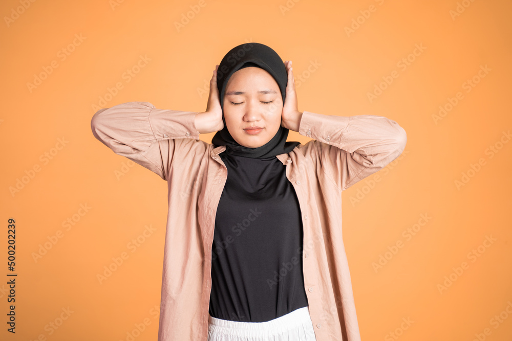 Woman in hijab cover her ear on isolated background Woman in hijab cover her ear on isolated background