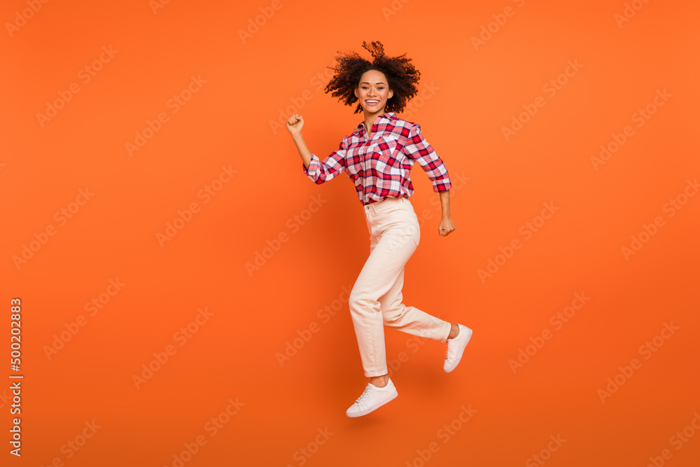 Full length body size view of attractive cheery sporty girl jumping running isolated on bright orange color background