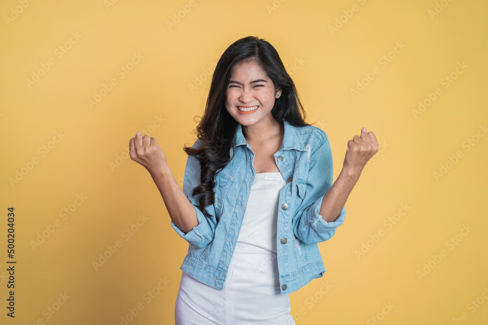 Excited young woman clenching hands while celebrating success on isolated background Excited young woman clenching hands while celebrating success on isolated background
