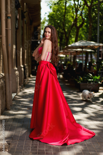 Attractive beautiful girl in a red dress standing on the city