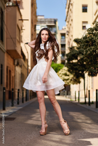 Young beautiful girl posing outdoor, wearing fashionable white dress. Summer style.